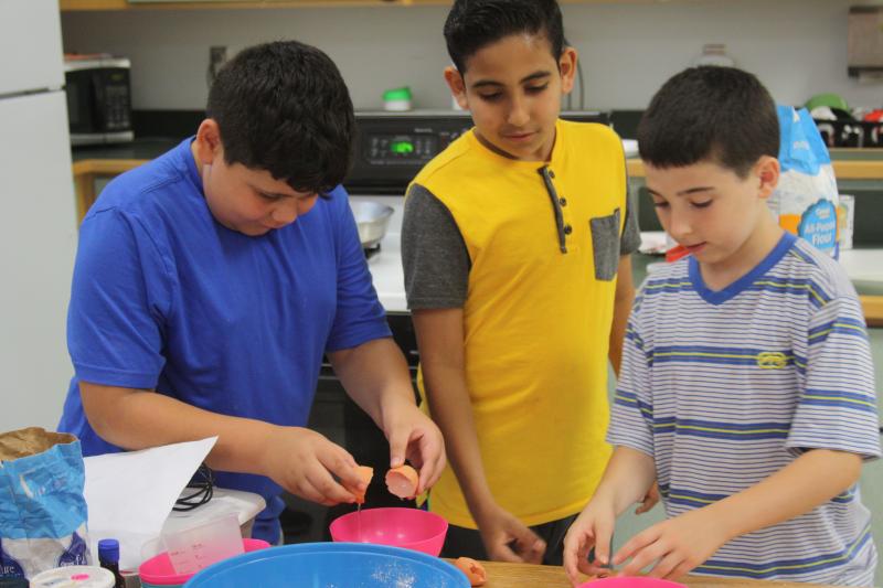 From left: Josiah Andersen, Sam Kaliny and Shawn Kimball crack eggs to make pancakes. BY MATTHEW BERNAT